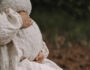 Pregnant woman holding her belly. Only her torso is visible. From the side.